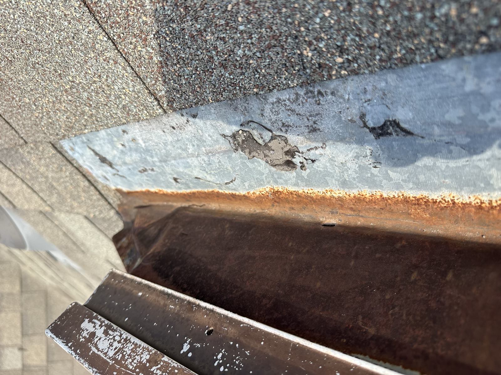 Corroded valley metal with granule buildup in the gutter